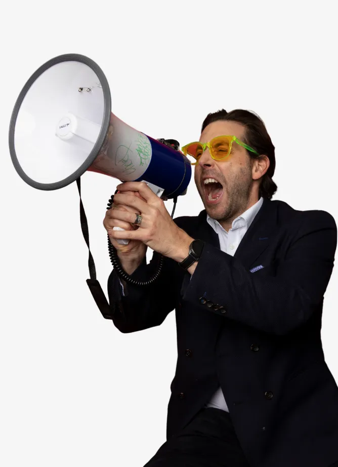 Man wearing a suit ang glasses, shouting into a megaphone.